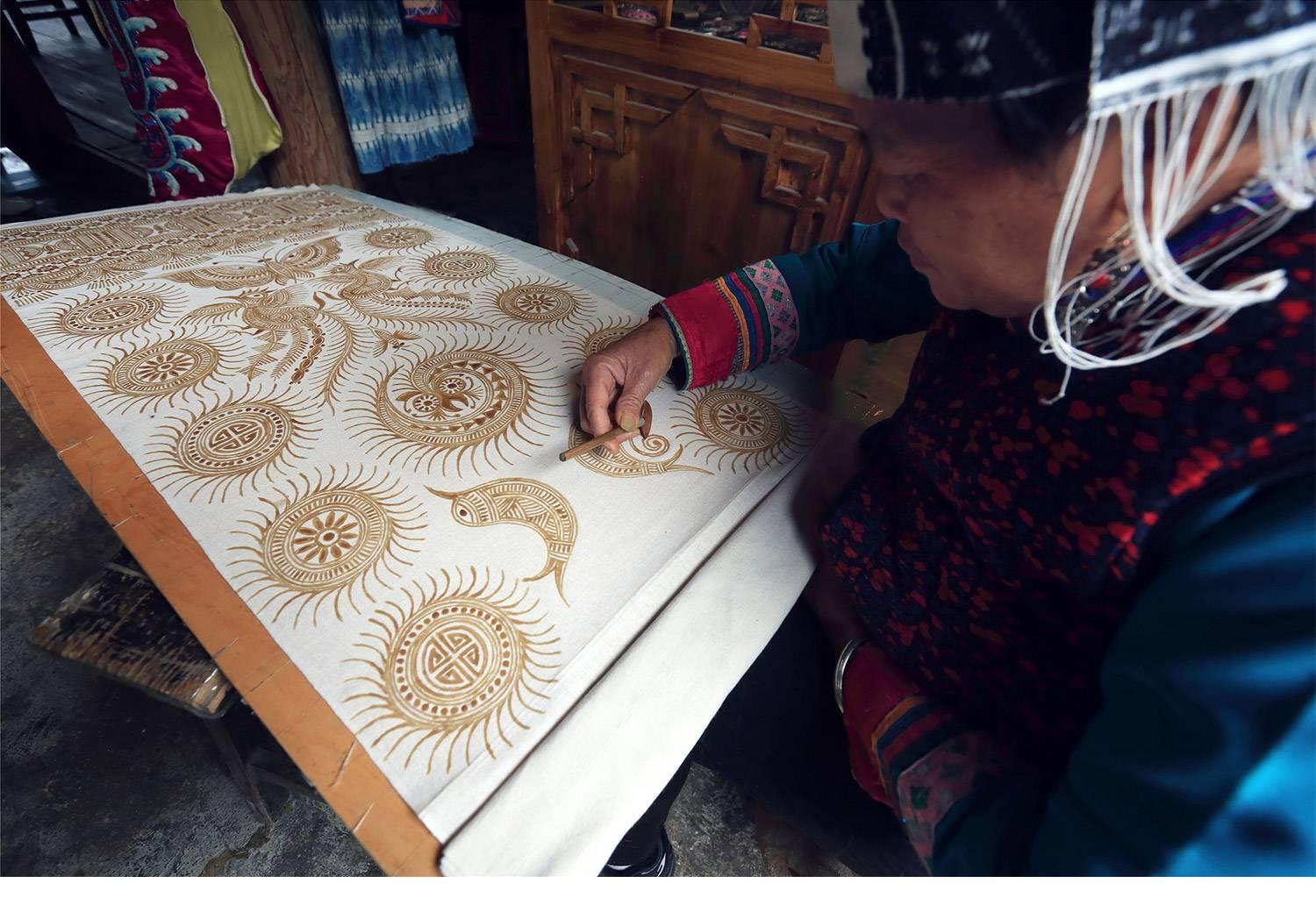 Close-up of an artisan applying wax to cloth using a traditional tool